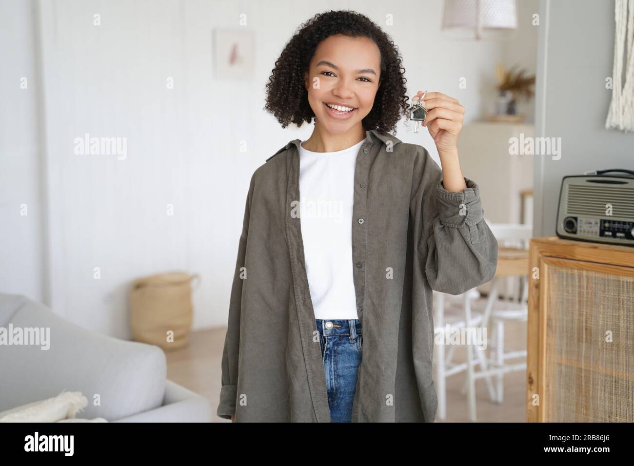 La ragazza felice mostra le chiavi del primo appartamento. Un adolescente sorridente tiene la chiave di casa, in piedi nella nuova casa. Il servizio di affitto di immobili pubblicizza il trasferimento. Foto Stock