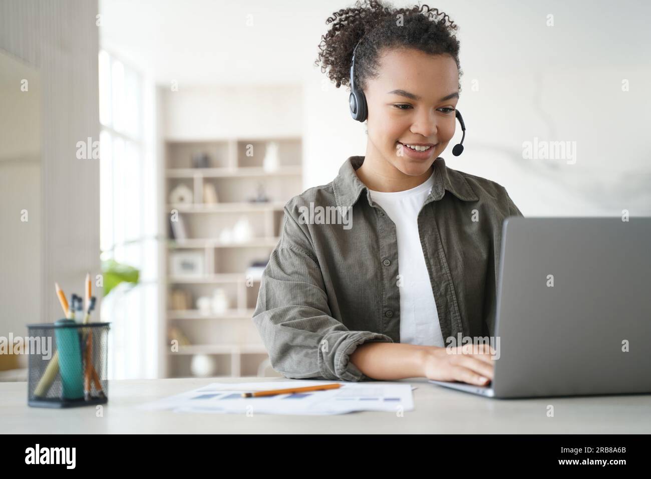 Sorridente studente birazziale delle superiori impara online a casa, indossando cuffie per studiare a distanza. Abbracciare l'istruzione a distanza. Foto Stock