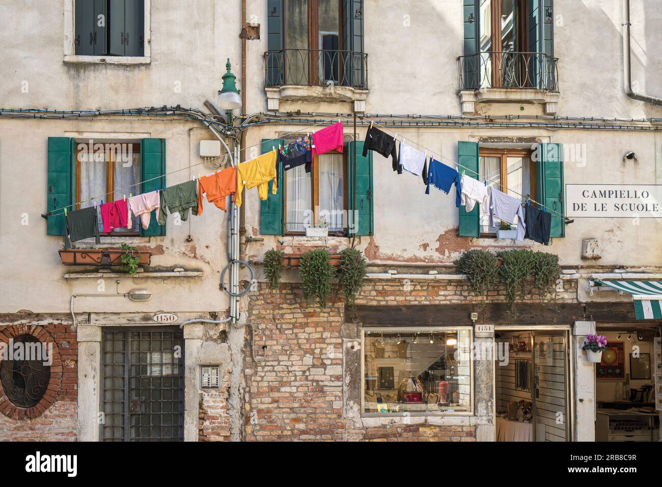 Scena tipica a Campiello de le scuole, Venezia, Italia. Lavare appeso in fila fuori dagli appartamenti e dai negozi sottostanti. Venezia è un patrimonio mondiale dell'UNESCO Foto Stock