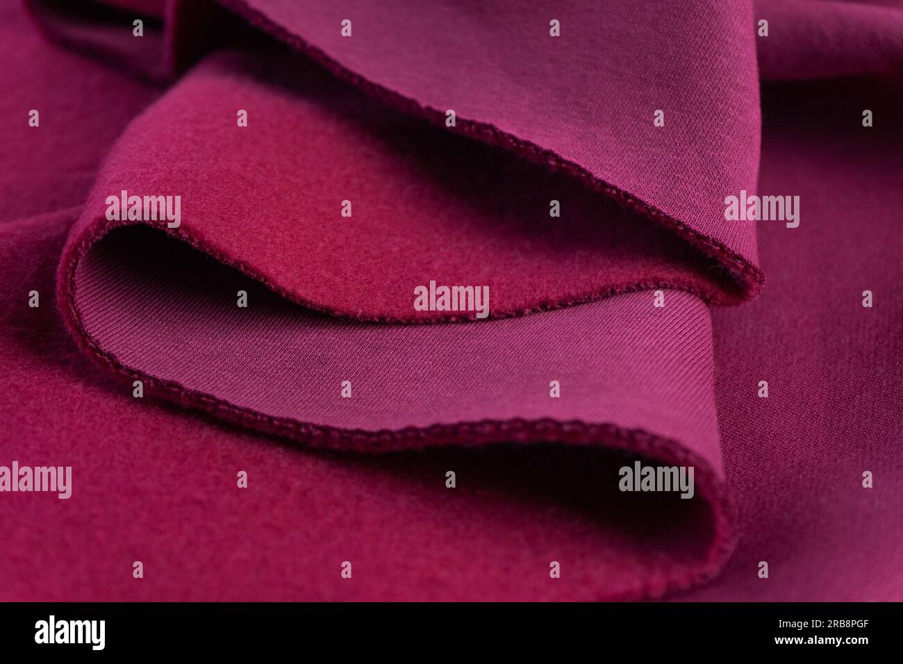 Strati di tessuto di amaranto rosa in spugna francese. Un pezzo di tessuto giace su splendide onde. tagliare per cucire Foto Stock