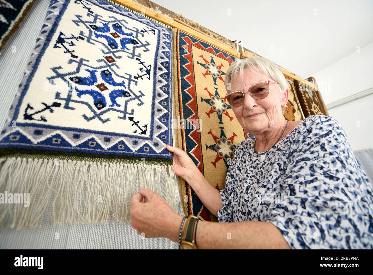 Freest, Germania. 8 luglio 2023. Il pensionato Giesela Zeitler esamina un tappeto da pesca dal più libero Museo di storia locale nella sala dei vigili del fuoco più libera durante la cerimonia di riconoscimento dei tappeti da pesca come patrimonio culturale immateriale. Carpet weaver Zeitler era impiegato dalla PGH Volkskunst nel Mar Baltico in epoca della RDT e ora tesseva tappeti da pesca nel suo tempo libero. Giesela Zeitler sarà onorata alla cerimonia di riconoscimento di oggi in libertà. Crediti: Frank Hormann/dpa-Zentralbild/dpa/Alamy Live News Foto Stock