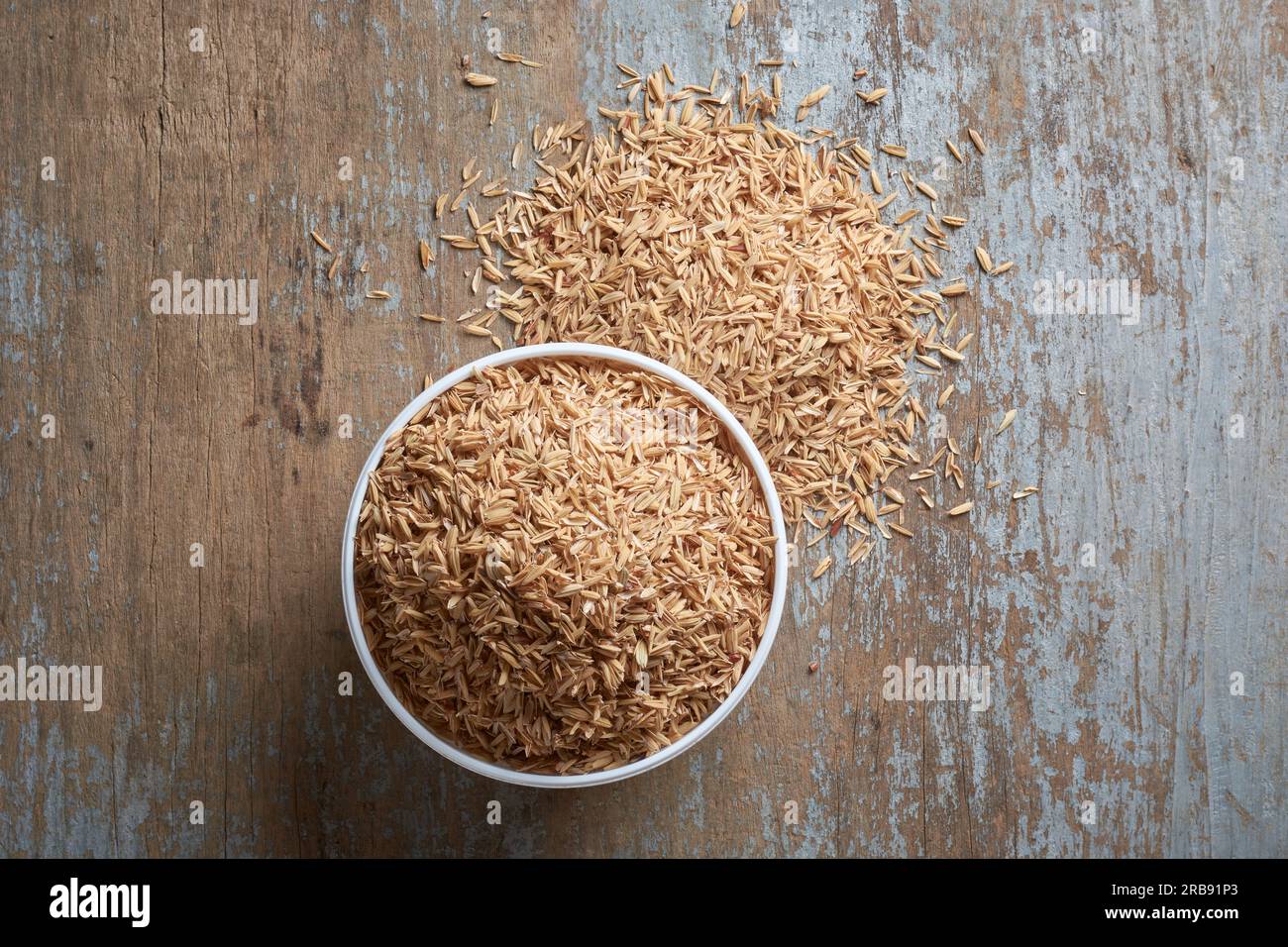 tazza di buccia di risone o di riso, detta pula di riso gialla, buccia di riso o scafo di riso, strato esterno del chicco di riso da utilizzare come mangime per animali, sparsa Foto Stock