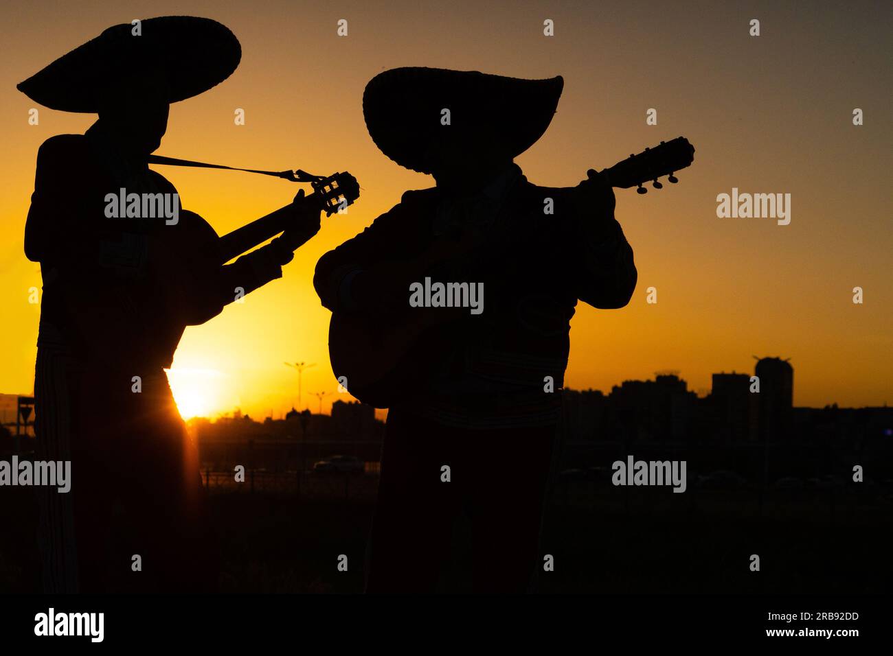 Sagome di una band mariachi di musicisti messicani sullo sfondo del panorama della città. Foto Stock