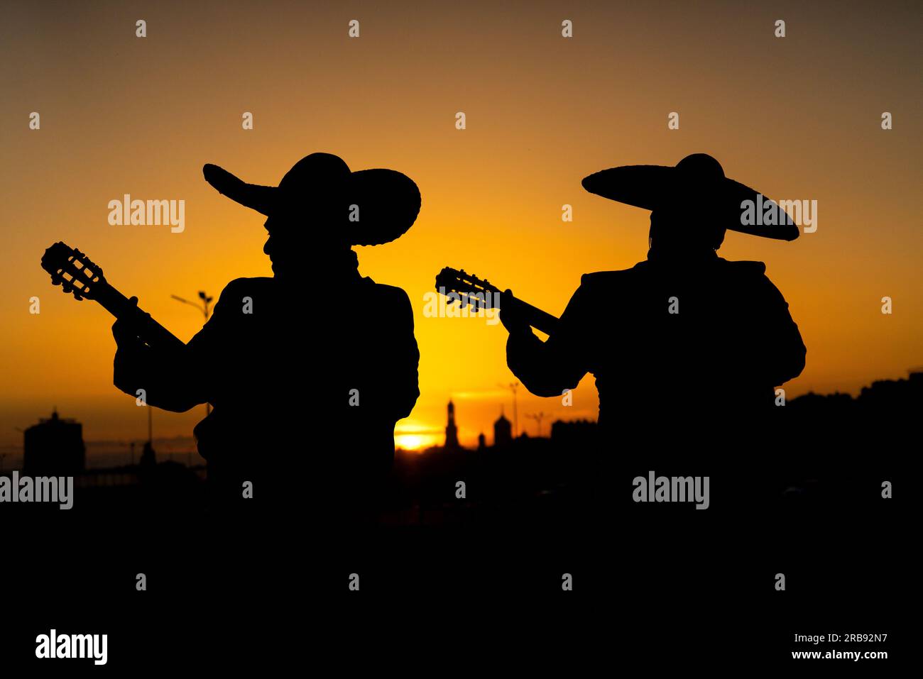 Sagome di una band mariachi di musicisti messicani sullo sfondo del panorama della città. Foto Stock