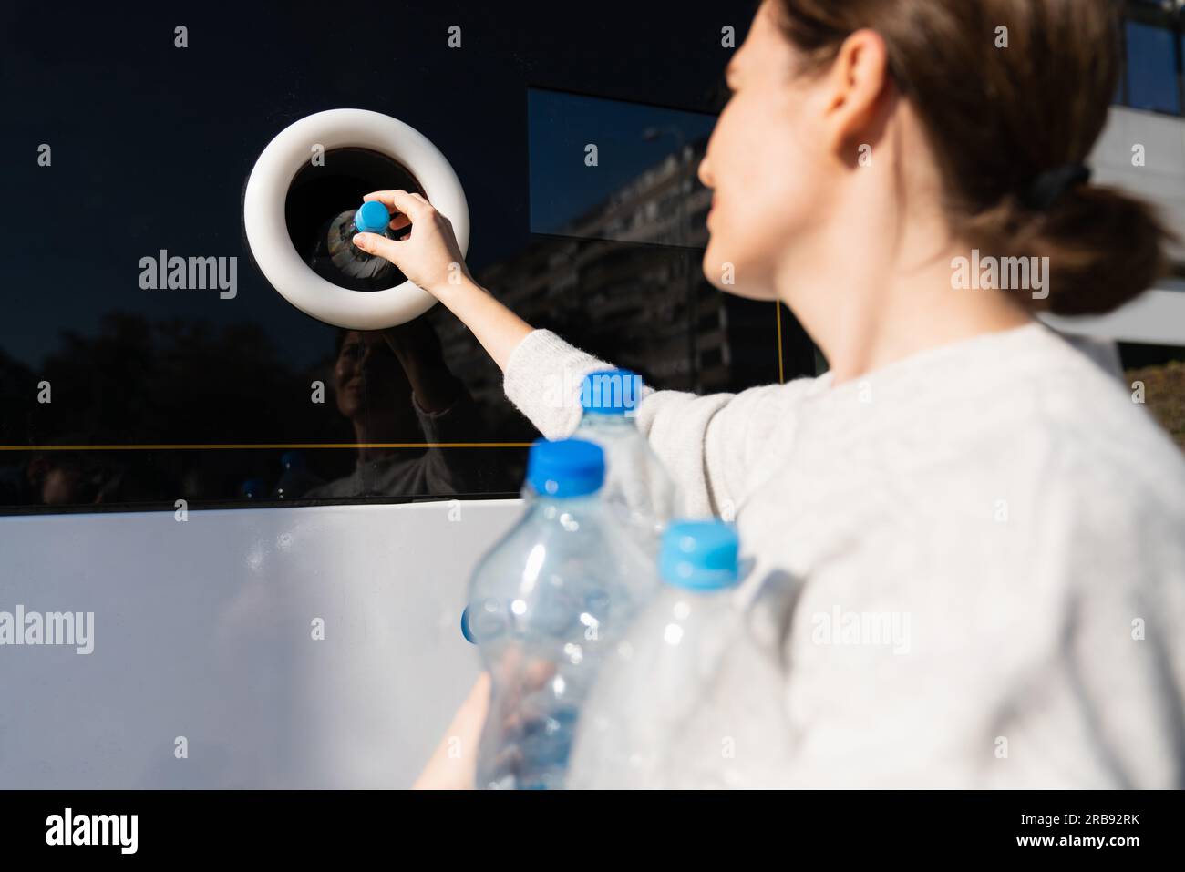 La donna usa una macchina self-service per ricevere bottiglie e lattine di plastica usate in una strada cittadina. Foto Stock