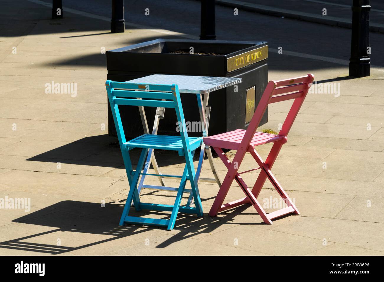 Due sedie pieghevoli in legno e tavolo pieghevole alla luce del sole, Kirkgate, Ripon City, North Yorkshire, Inghilterra, REGNO UNITO Foto Stock