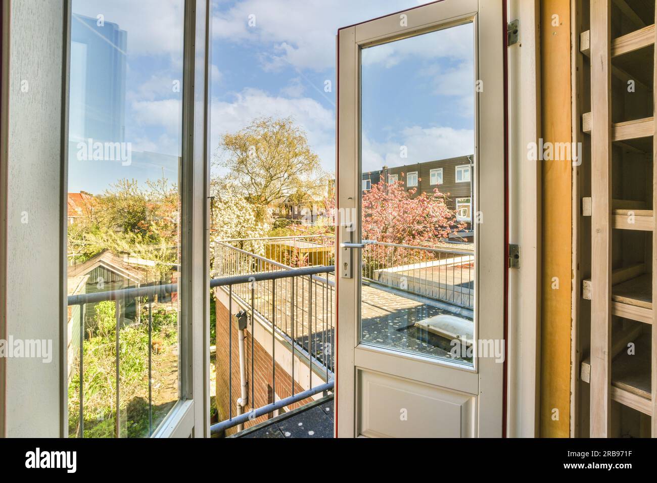 vista dall'interno di una casa attraverso una porta aperta su un balcone con alberi e case sullo sfondo Foto Stock