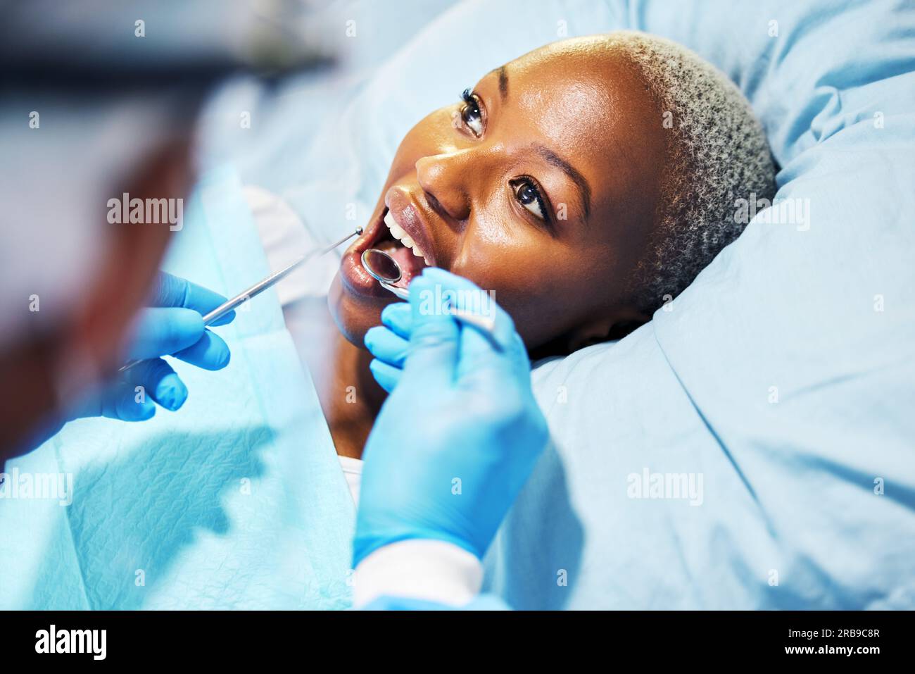 Dentista, ispezione e donna con strumenti in bocca in clinica per cavità, sbiancamento dei denti e aiuto mano per il dolore. Chirurgo odontoiatrico, paziente africano e. Foto Stock