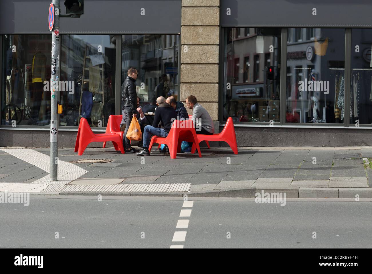 Persone sedute all'esterno su sedie di plastica rossa e che parlano di Francoforte sul meno, Germania Foto Stock