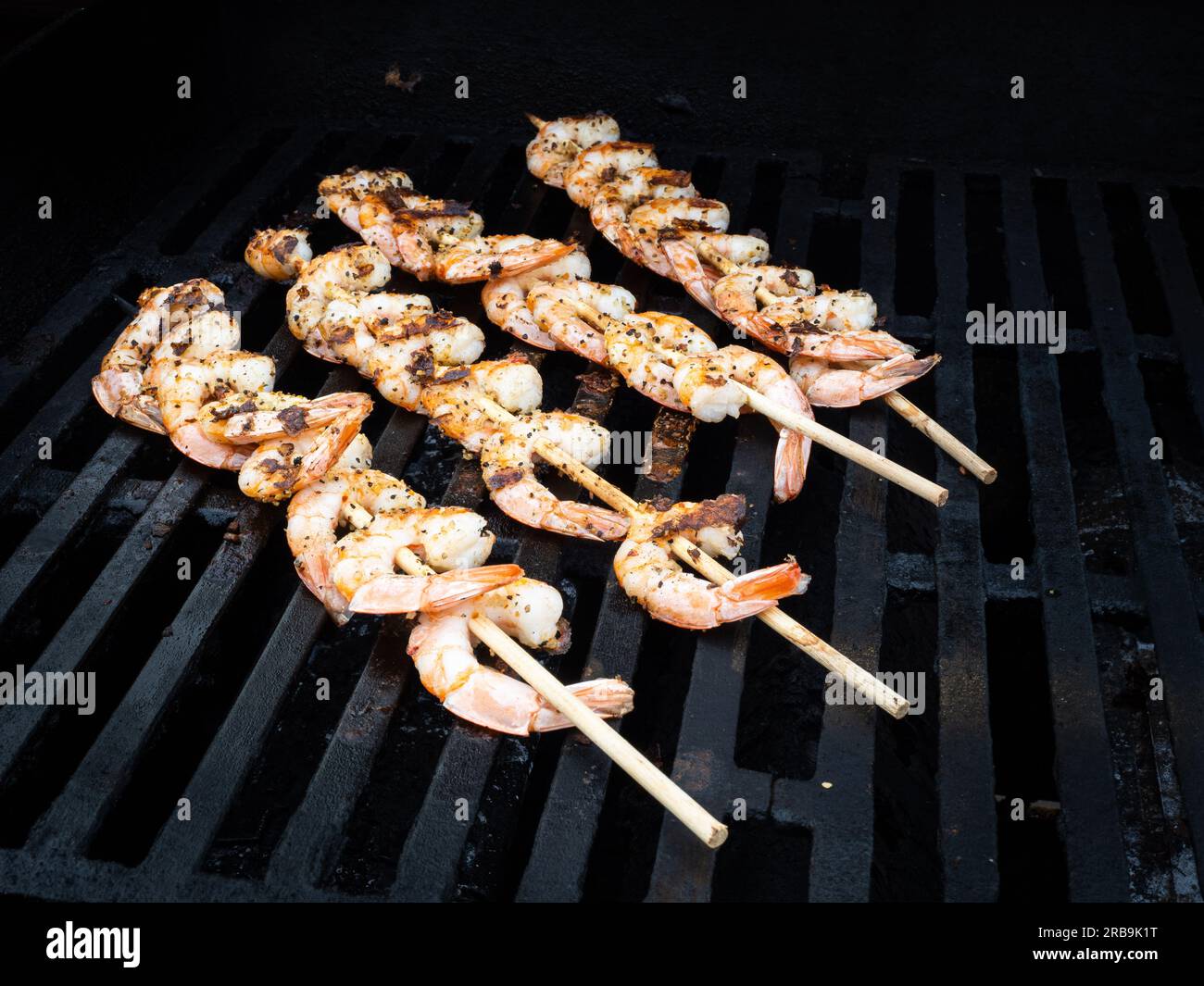 Luccicanti su un frizzante barbecue alla griglia, succulenti spiedini di gamberi stuzzicano con il loro aroma appetitoso. Foto Stock