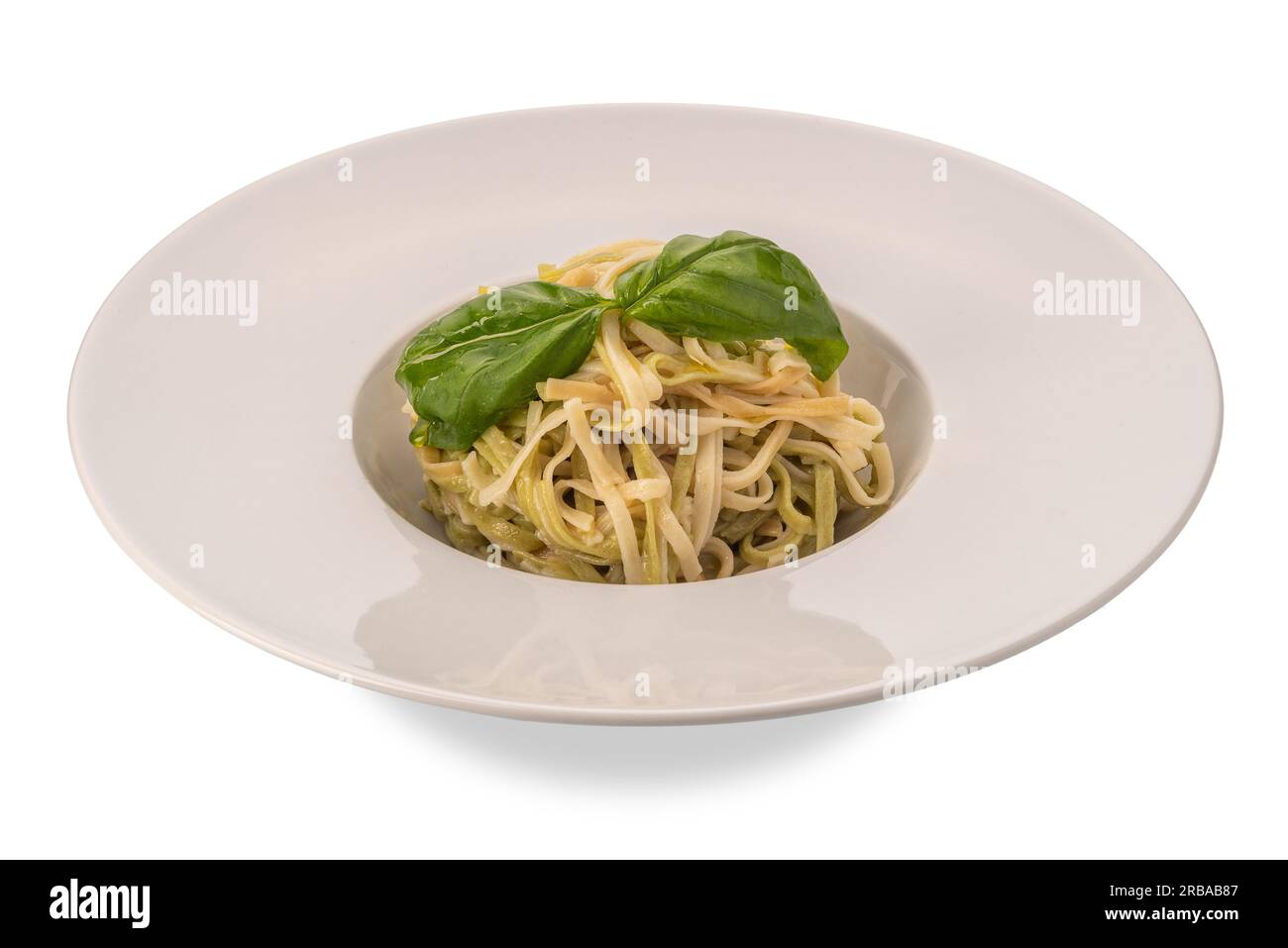 Linguini di due tipi verdure bianche e verdi con foglie di basilico e olio d'oliva in piatto isolato su bianco con sentiero di ritaglio Foto Stock