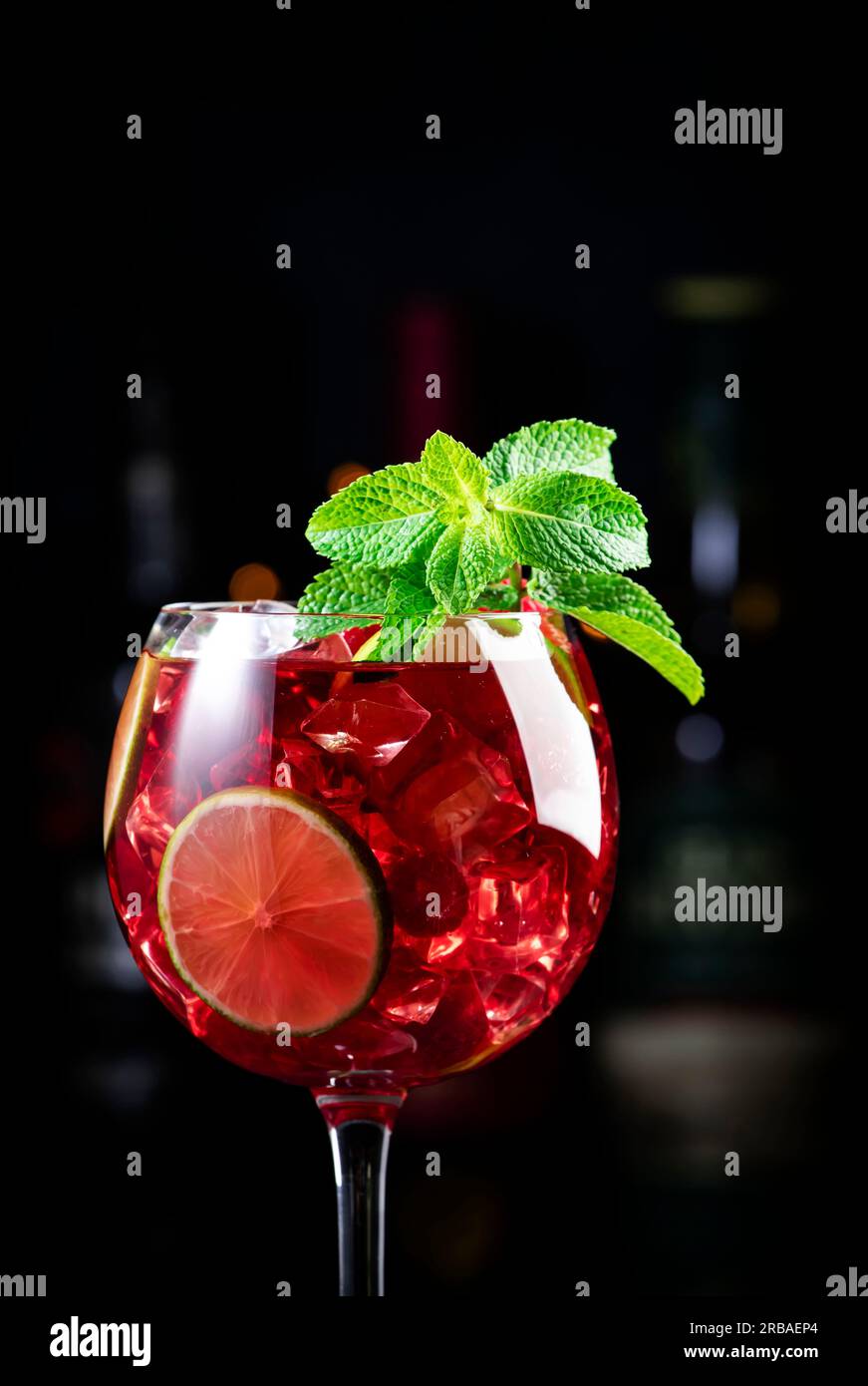 Cocktail alcolico Royal limonade con tequila, gin secco, rum bianco, vodka, liquore, lime, lamponi e ghiaccio nel bicchiere da vino. Bancone bar nero ba Foto Stock