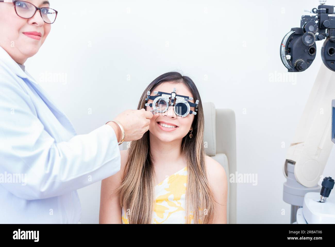 Optometrista femminile che esamina il paziente con il telaio di prova optometrista. Paziente sorridente con telaio di prova optometrista Foto Stock