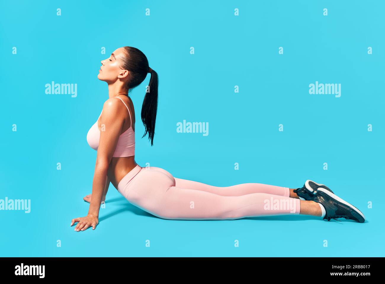 Fitness donna fare esercizio cobra su sfondo blu Foto Stock