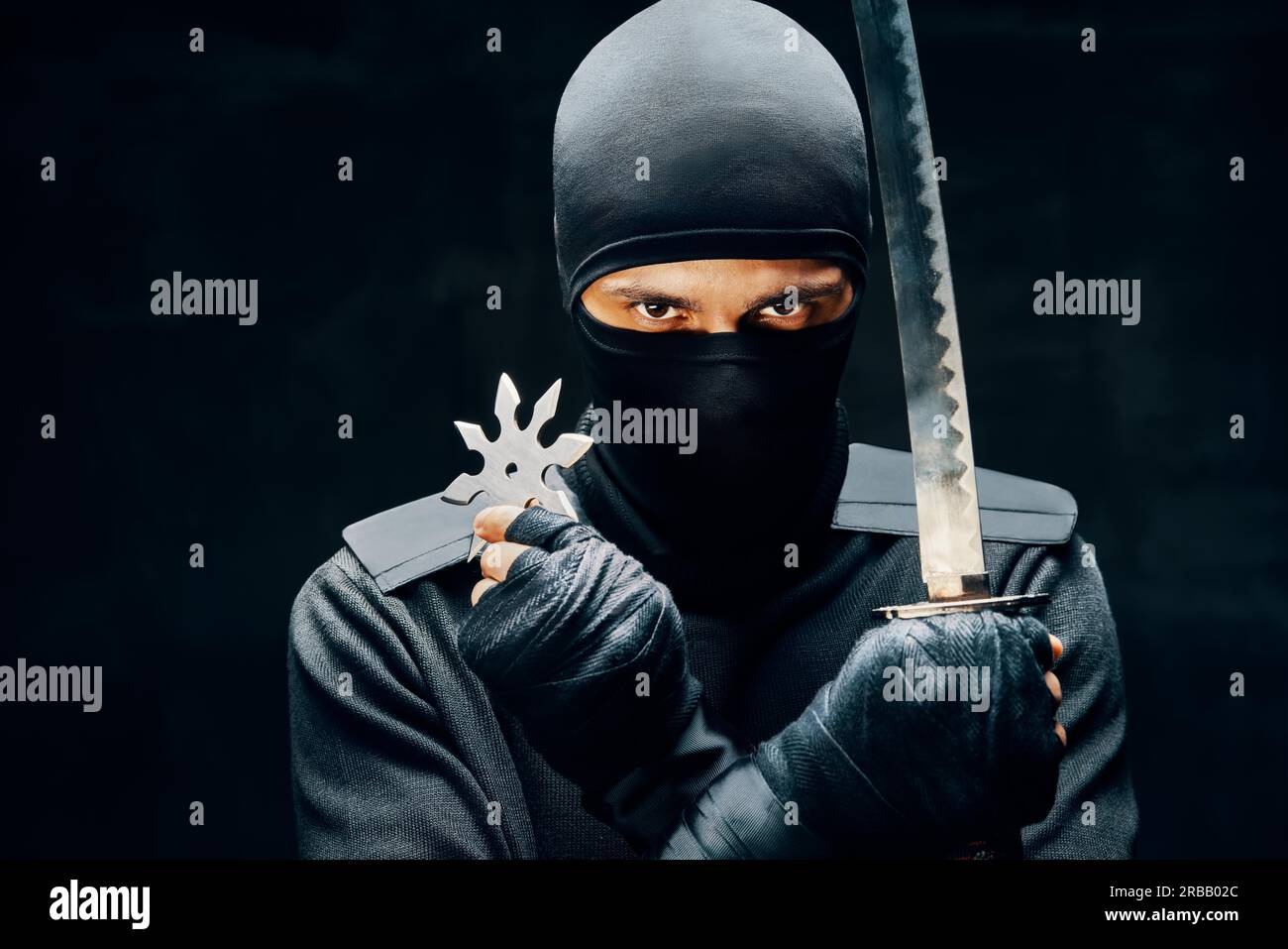 Ninja samurai guerriero combattente con una spada e shuriken su sfondo nero. Concetto di combattente giapponese Foto Stock