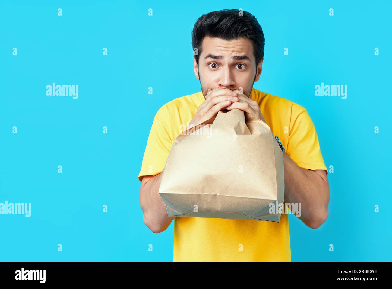 Giovane bell'uomo che ha un attacco di panico su sfondo blu Foto Stock