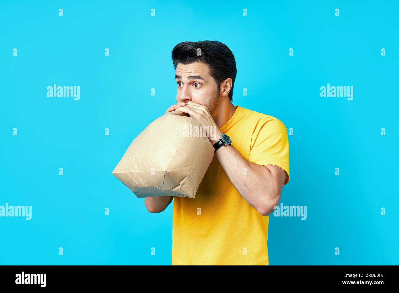 Giovane bell'uomo che ha un attacco di panico su sfondo blu Foto Stock
