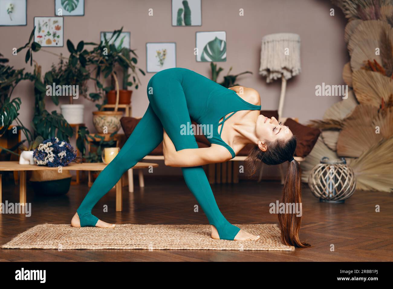 Giovane donna sportiva che pratica yoga a casa facendo la posa del triangolo rivoltato. Parivrtta baddha trikonasana. Concetto di benessere e stile di vita sano Foto Stock