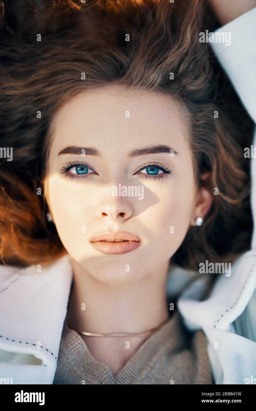 Primo piano ritratto di bella giovane donna con capelli ondulati lunghi alla luce del sole all'aperto. Bellezza femminile, trucco e cosmetici Foto Stock