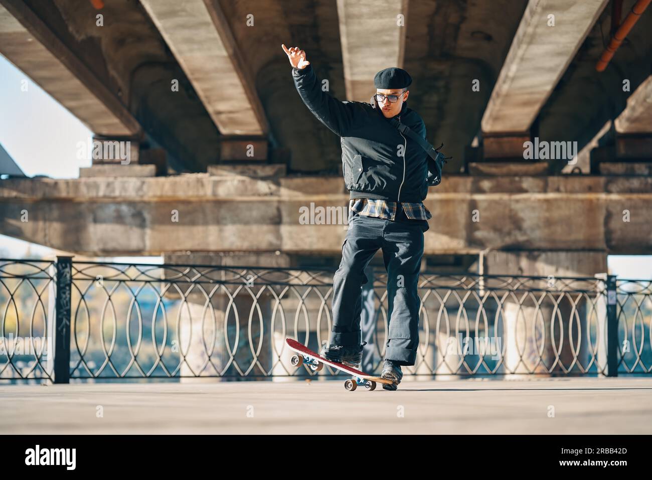 Lo skateboarder fa il trucco ollie sullo sfondo urbano della strada. Concetto di sport estremi Foto Stock