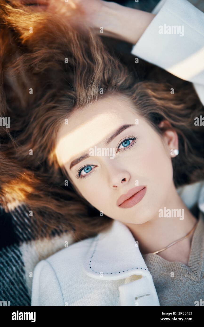 Primo piano ritratto di bella giovane donna con capelli ondulati lunghi alla luce del sole all'aperto. Bellezza femminile, trucco e cosmetici Foto Stock