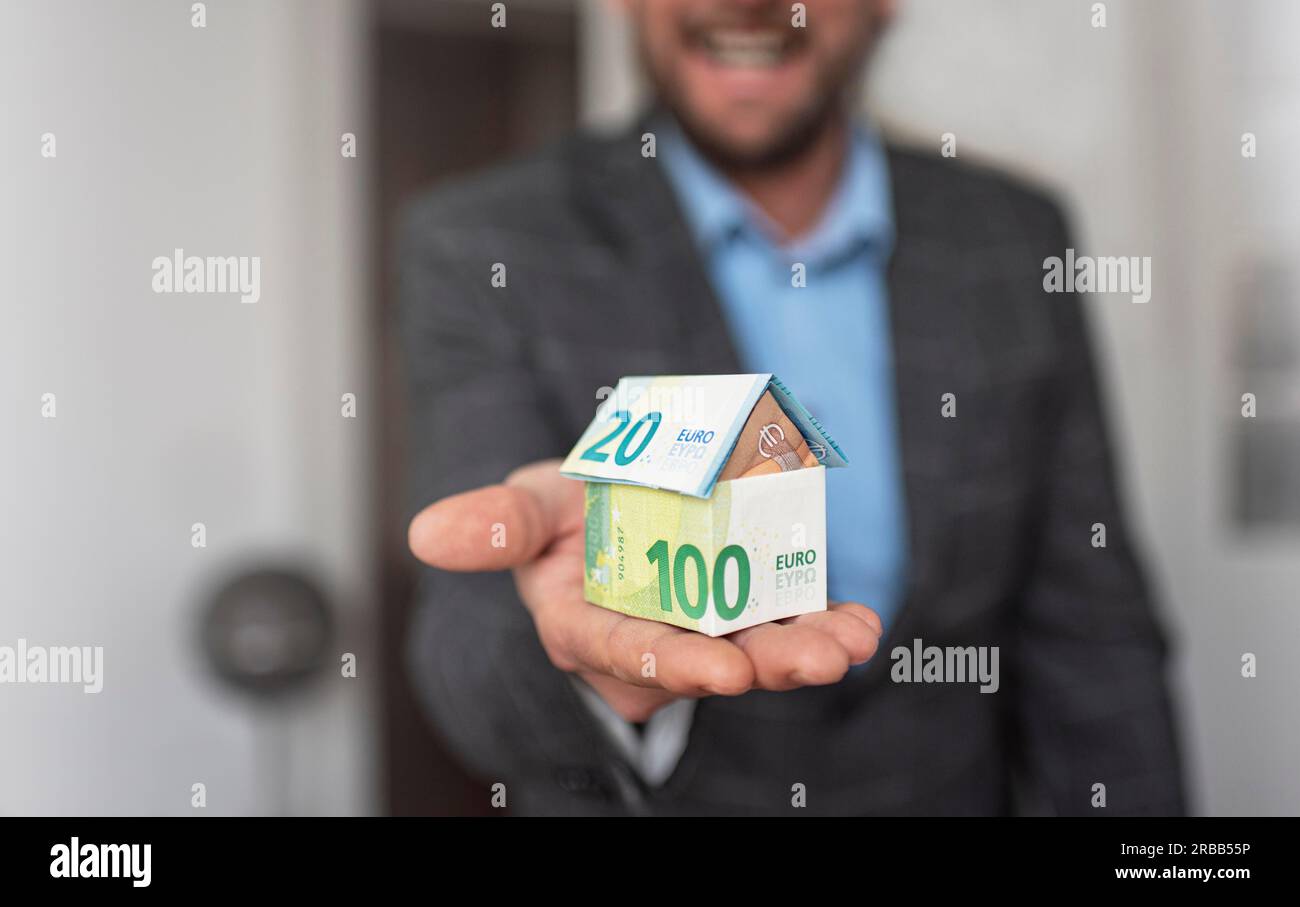 Un uomo tiene in mano una casa di banconote in euro Foto Stock