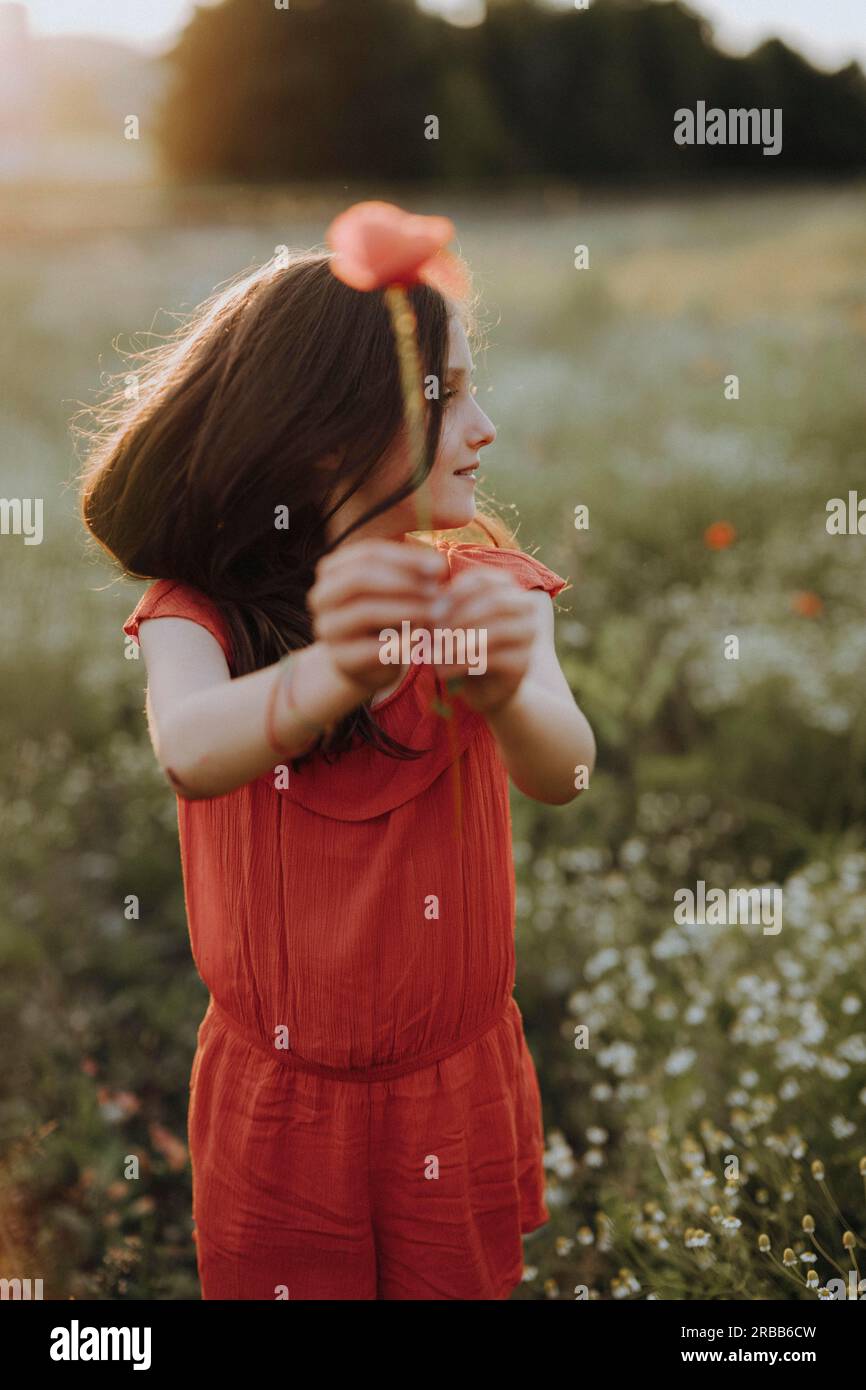 Ragazza con un vestito rosso in un prato di papavero Foto Stock