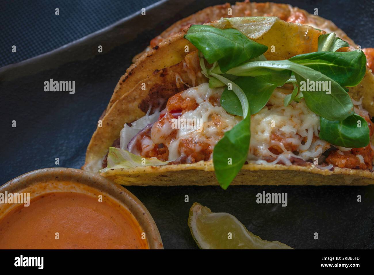 Saporiti tacos in stile messicano con succulenti gamberetti, pomodori, formaggio, peperoncino e cipolle, Servito con un contorno di salsa messicana calda e piccante per una Foto Stock