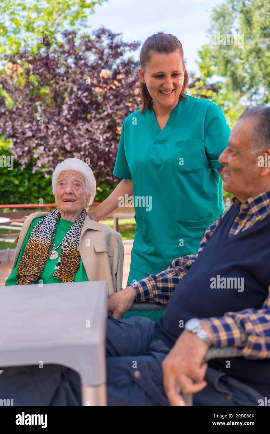 Due anziani con l'infermiera nel giardino di una casa di cura o di una casa di riposo, vecchio e anziano Foto Stock