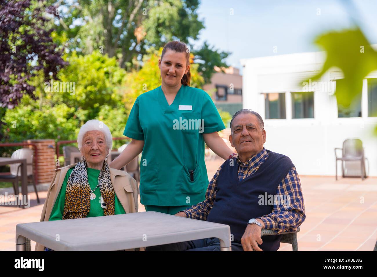 Ritratto di due anziani con l'infermiera nel giardino di una casa di cura o di una casa di riposo, vecchio e anziano Foto Stock