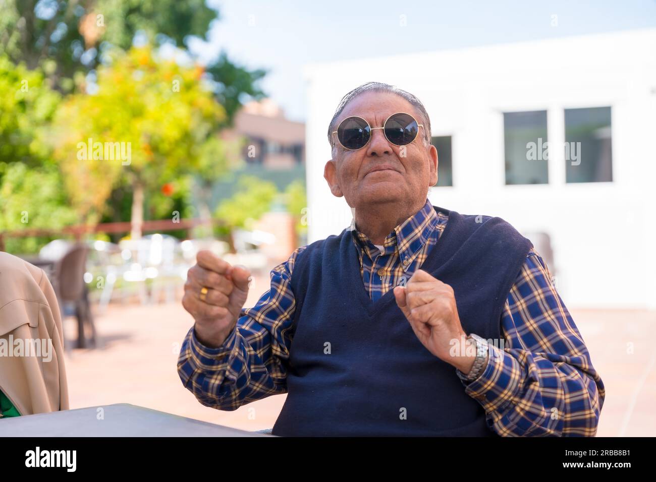 Un anziano che balla nel giardino di una casa di cura o di una casa di riposo a una festa estiva indossando occhiali da sole Foto Stock