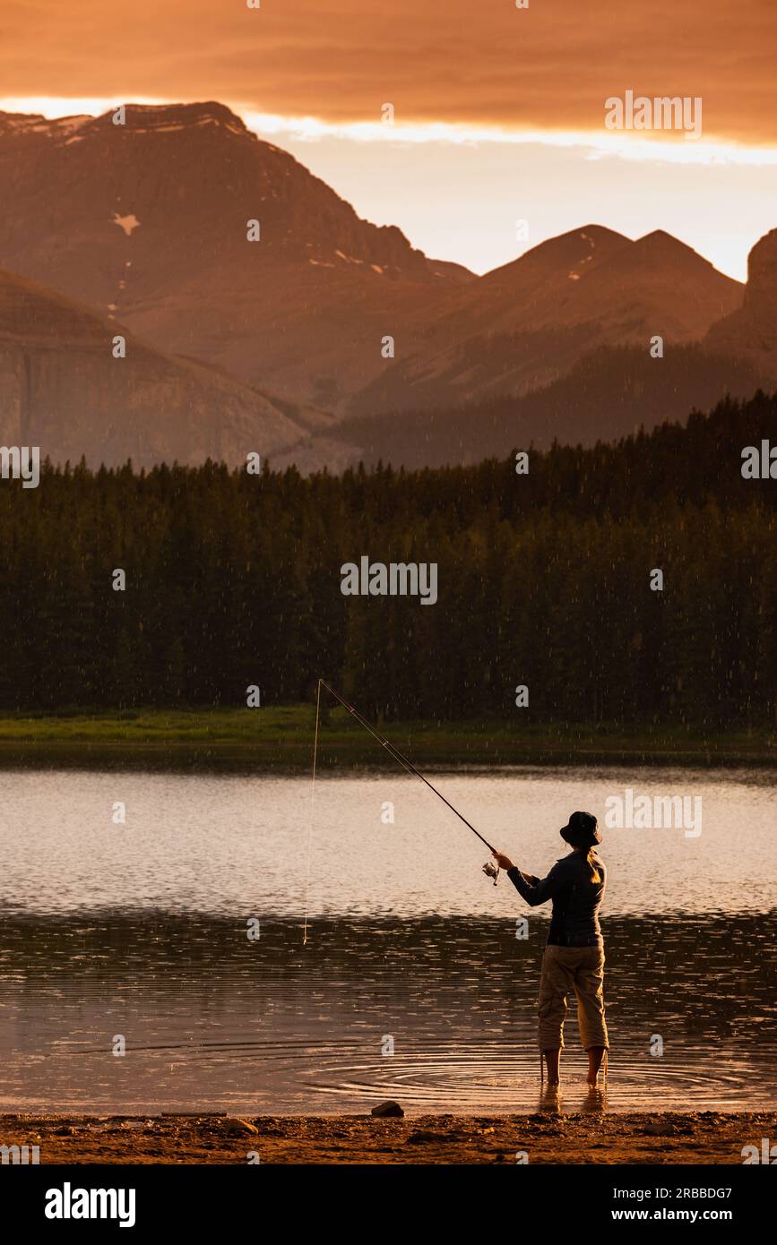 Pesca al tramonto - giovane donna che pesca al lago Margaret nell'area Waiparous dell'Alberta Canada Foto Stock