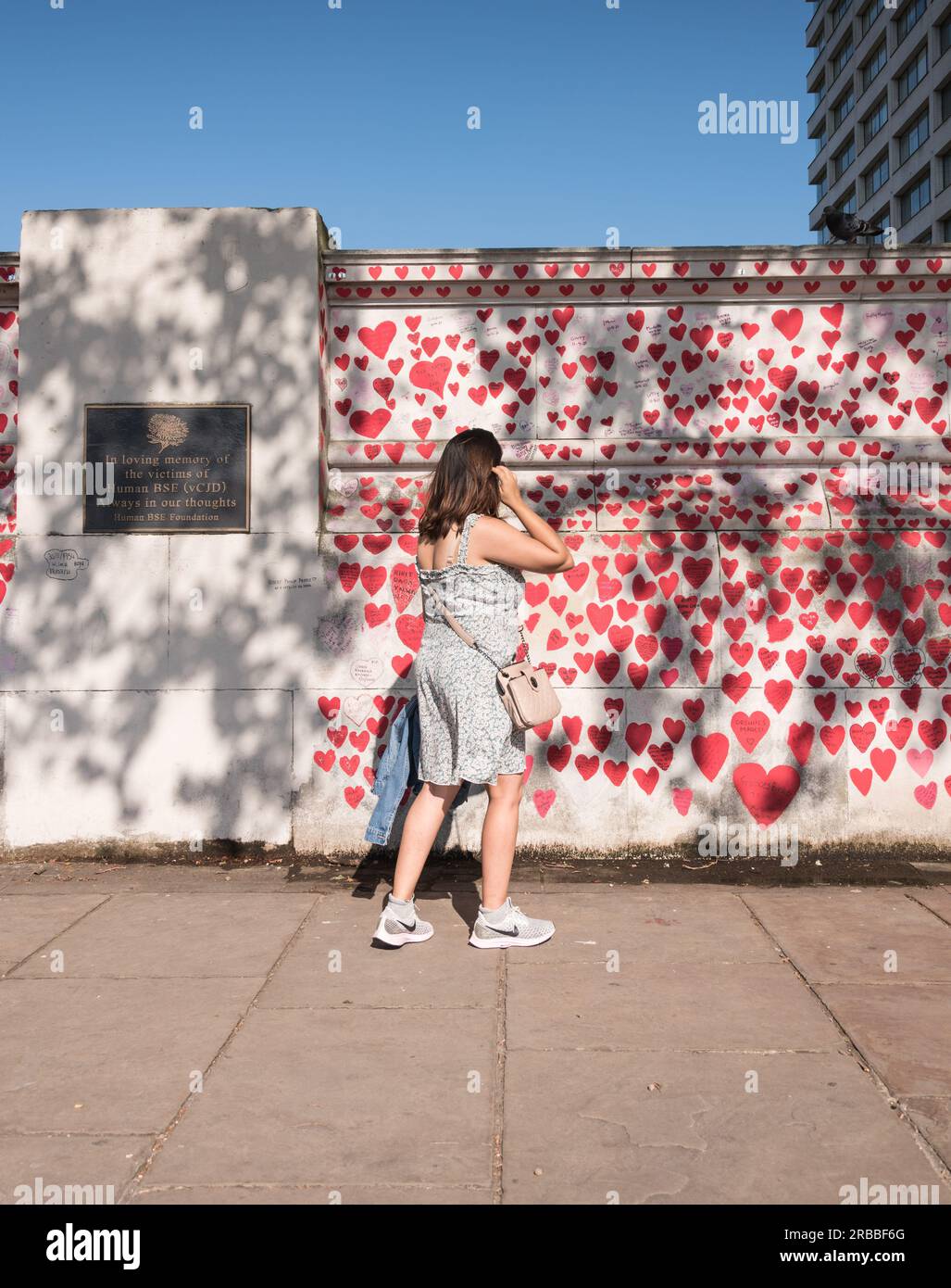 Una donna che tocca un cuore sul National Covid Memorial Wall, Londra, Inghilterra, Regno Unito. Foto Stock