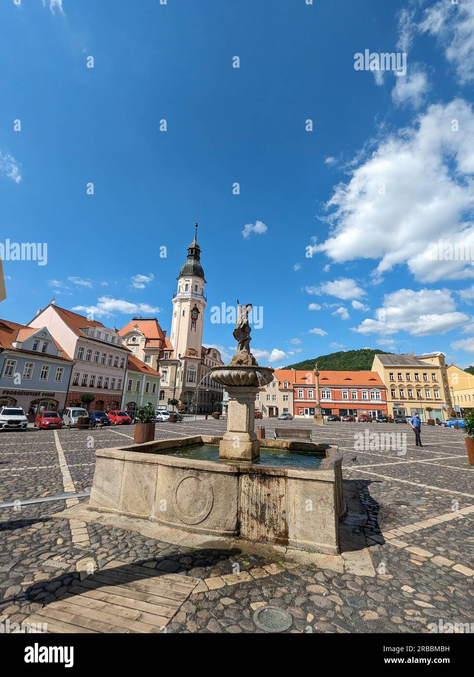 Bilina, repubblica Ceca, centro storico con fontane e piazza in pietra ciottolosa, chiese e castello sopra la città vecchia, panorama della Boemia settentrionale Foto Stock