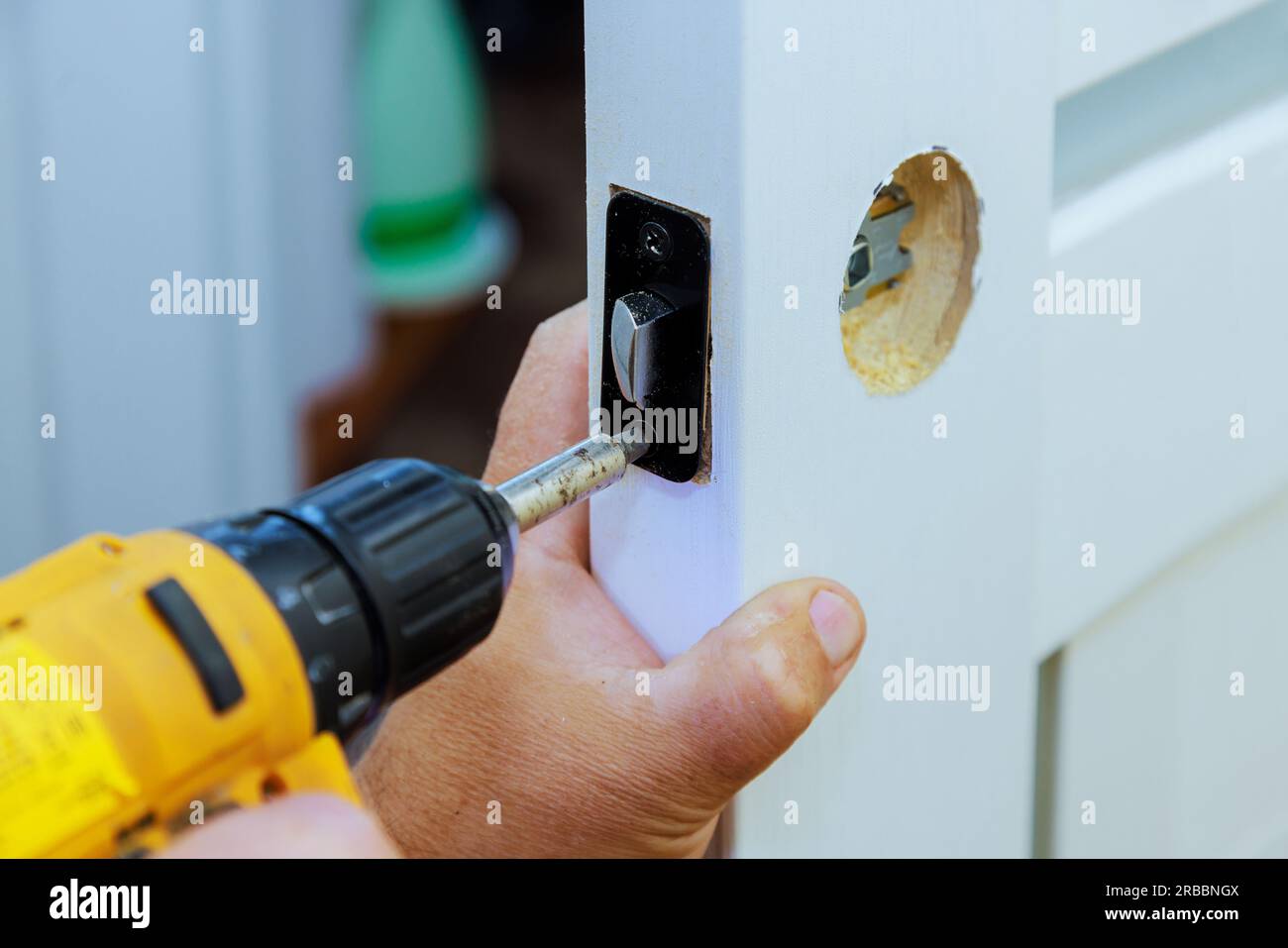Con l'aiuto di un cacciavite, completa l'installazione della serratura sulla porta interna. Foto Stock