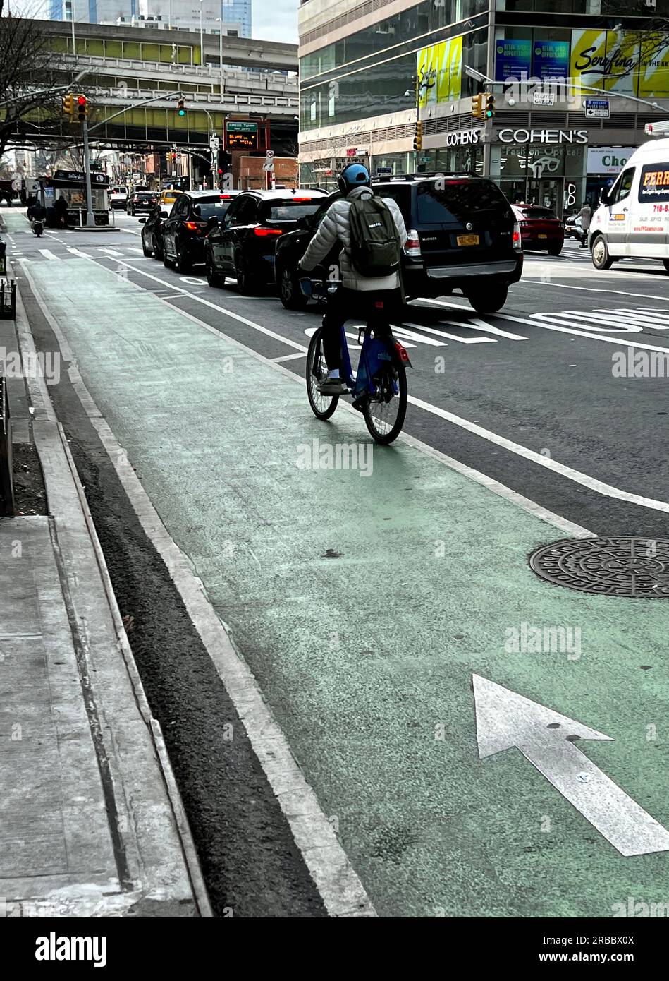 I pendolari percorrono la pista ciclabile in una trafficata strada di New York. Foto Stock