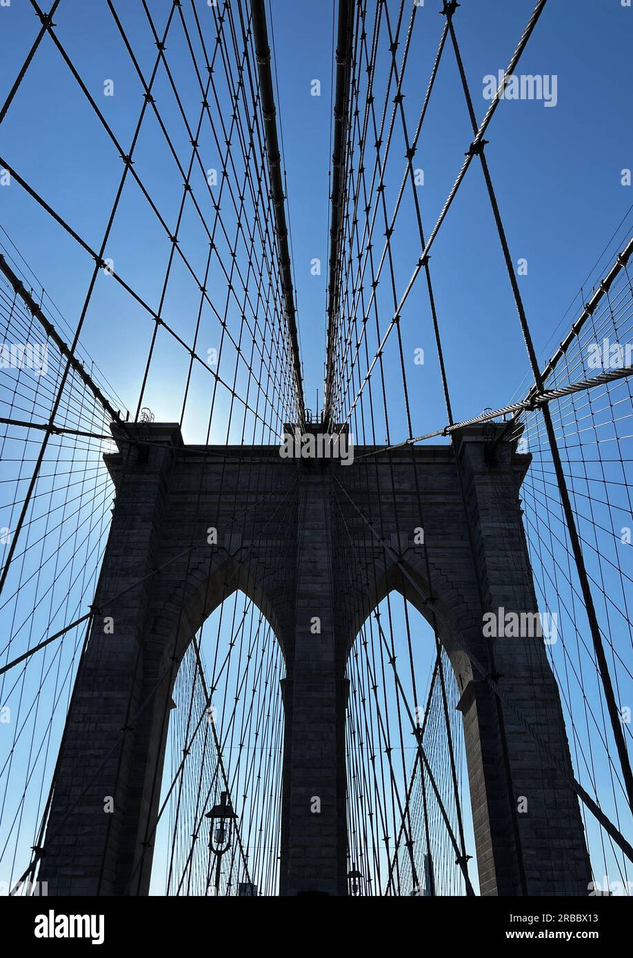 Cavi che conducono ad una torre sul Ponte di Brooklyn contro un cielo blu Foto Stock