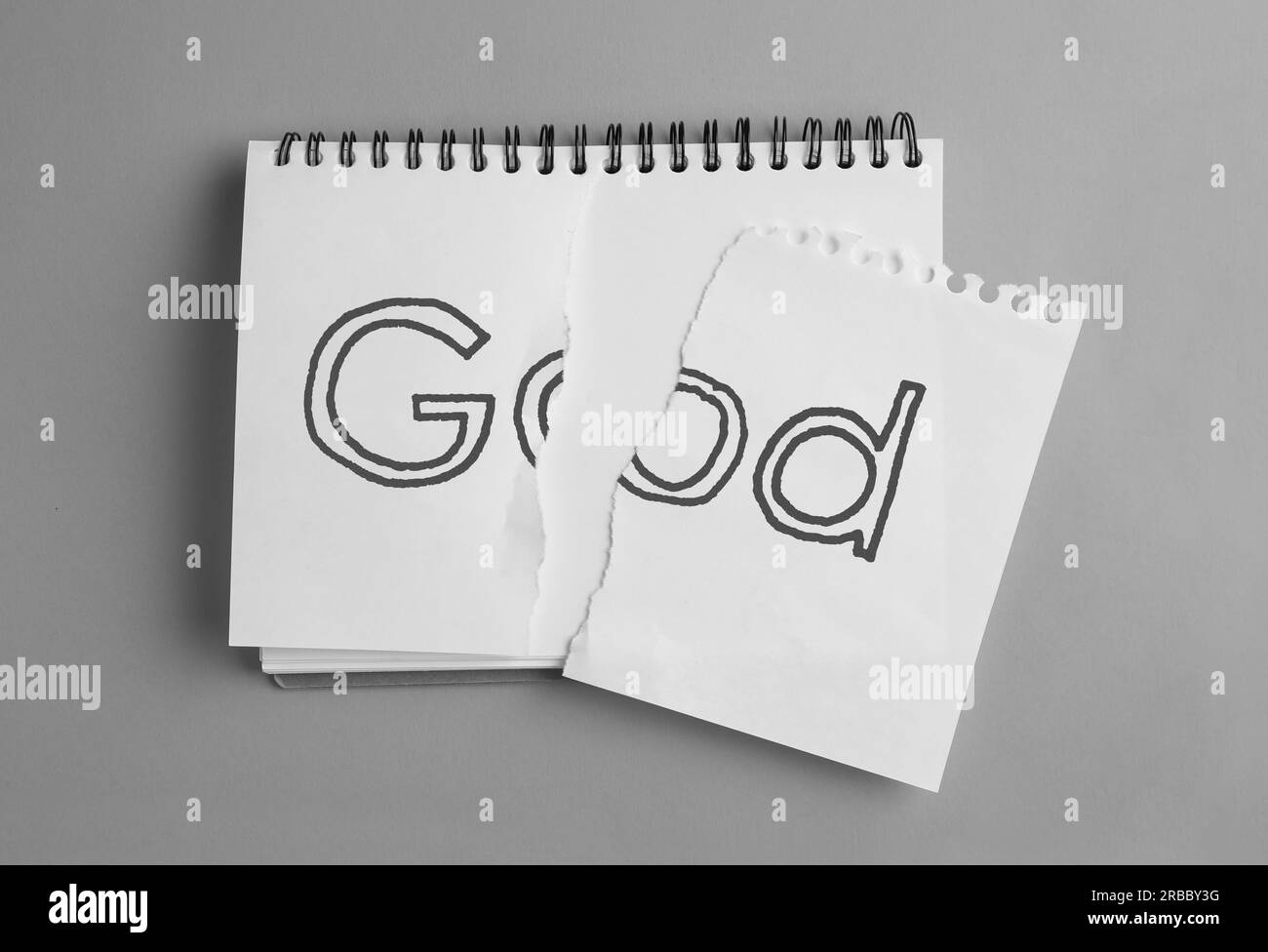 Ateismo come posizione religiosa. Carta strappata con la parola Dio nel notebook su sfondo grigio, vista dall'alto Foto Stock