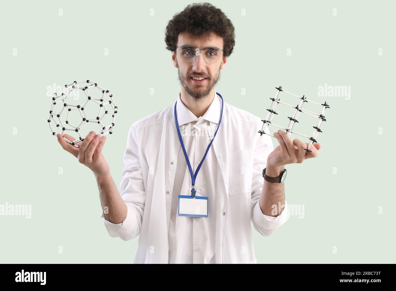 Studente maschio con modelli molecolari su sfondo verde Foto Stock