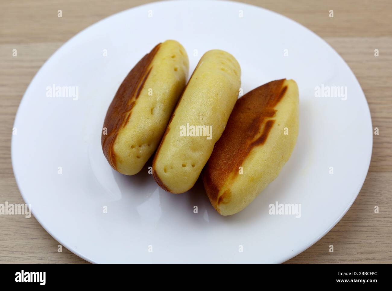 spuntino indonesiano chiamato kue pukis, a base di uova e farina con condimento di formaggio servito su un piatto Foto Stock