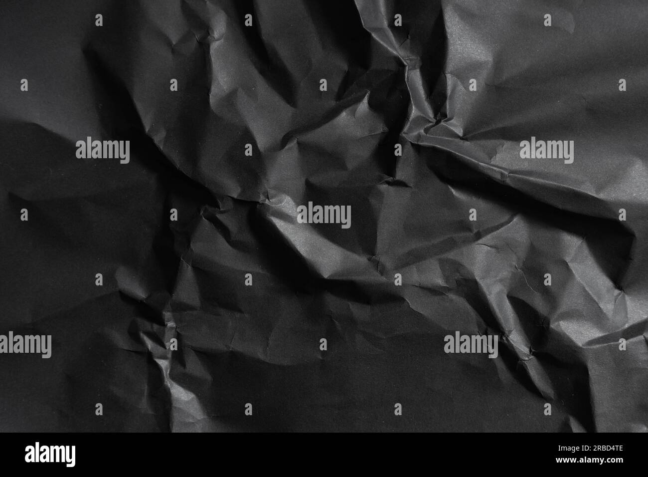 Grana di carta nera stropicciata su sfondo poco chiaro Foto Stock