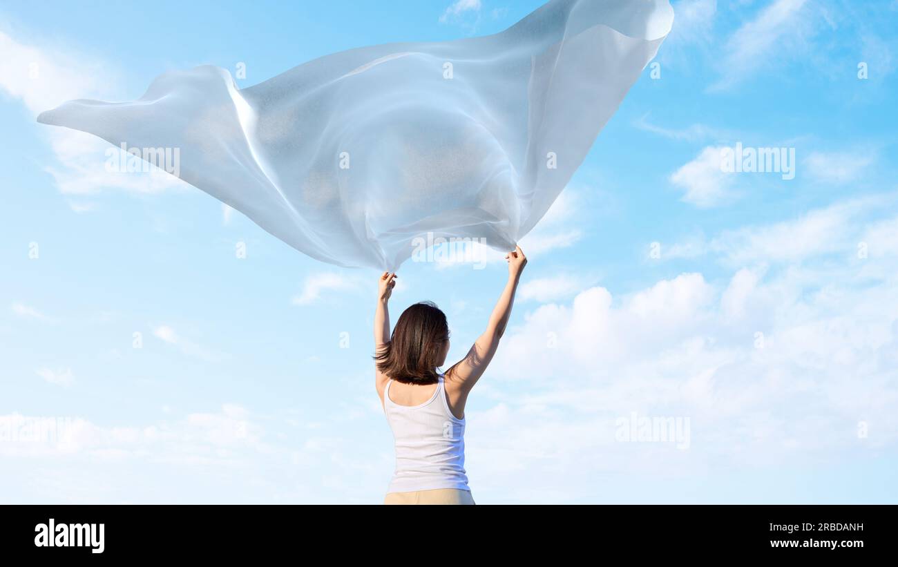 Una donna che sbatte il suo panno verso il cielo Foto Stock