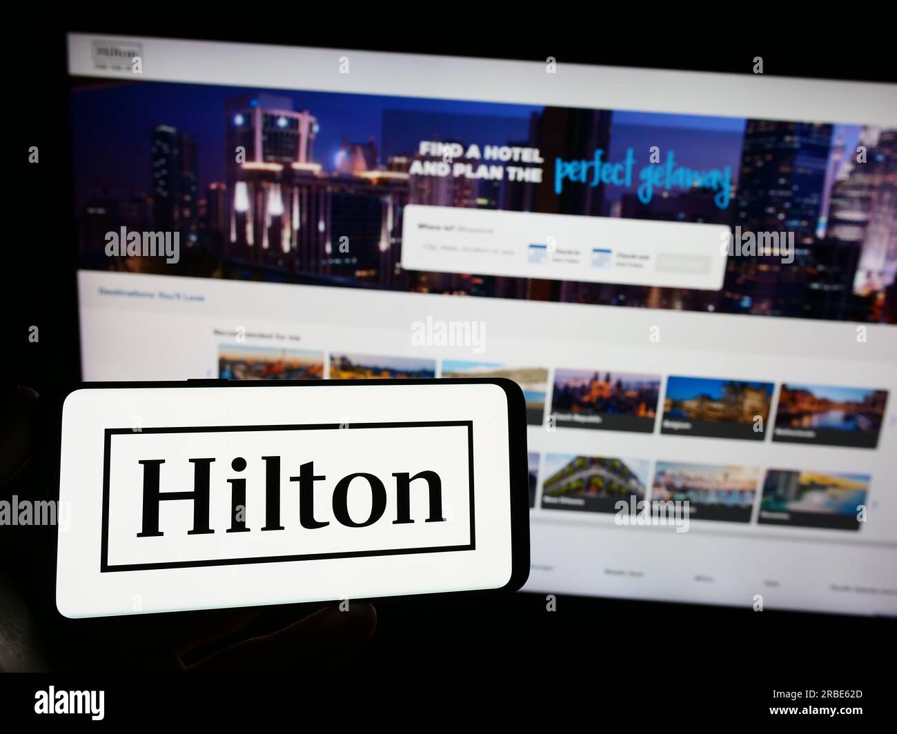 Persona che possiede uno smartphone con il logo della società statunitense Hilton Worldwide Holdings Inc. Sullo schermo davanti al sito Web. Concentrarsi sul display del telefono. Foto Stock