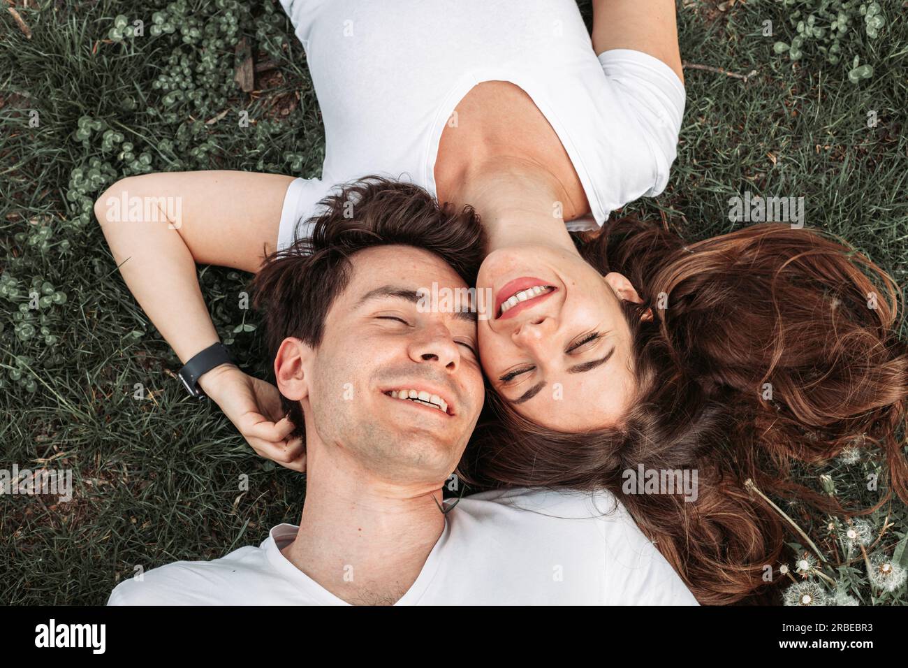 Vista dall'alto di una giovane coppia romantica sdraiata nell'erba Foto Stock