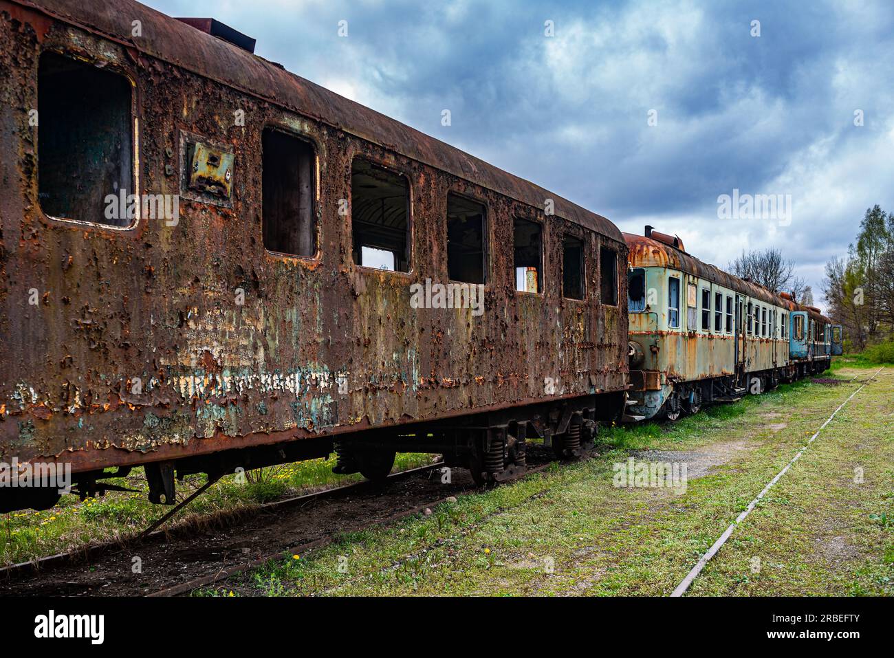 Vecchia carrozza ferroviaria arrugginita per passeggeri con più unità elettriche abbandonate sul campo cimitero dei treni Foto Stock