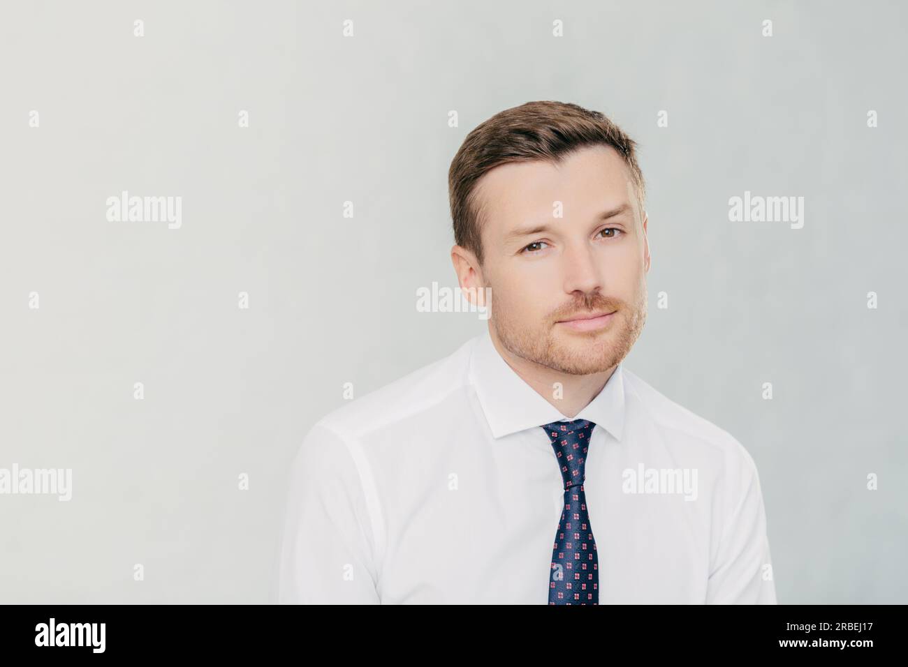 Un leader maschile di successo pensa alla partnership, cerca un miglioramento finanziario. Indossa camicia e cravatta bianche. Isolato su sfondo bianco. Foto Stock