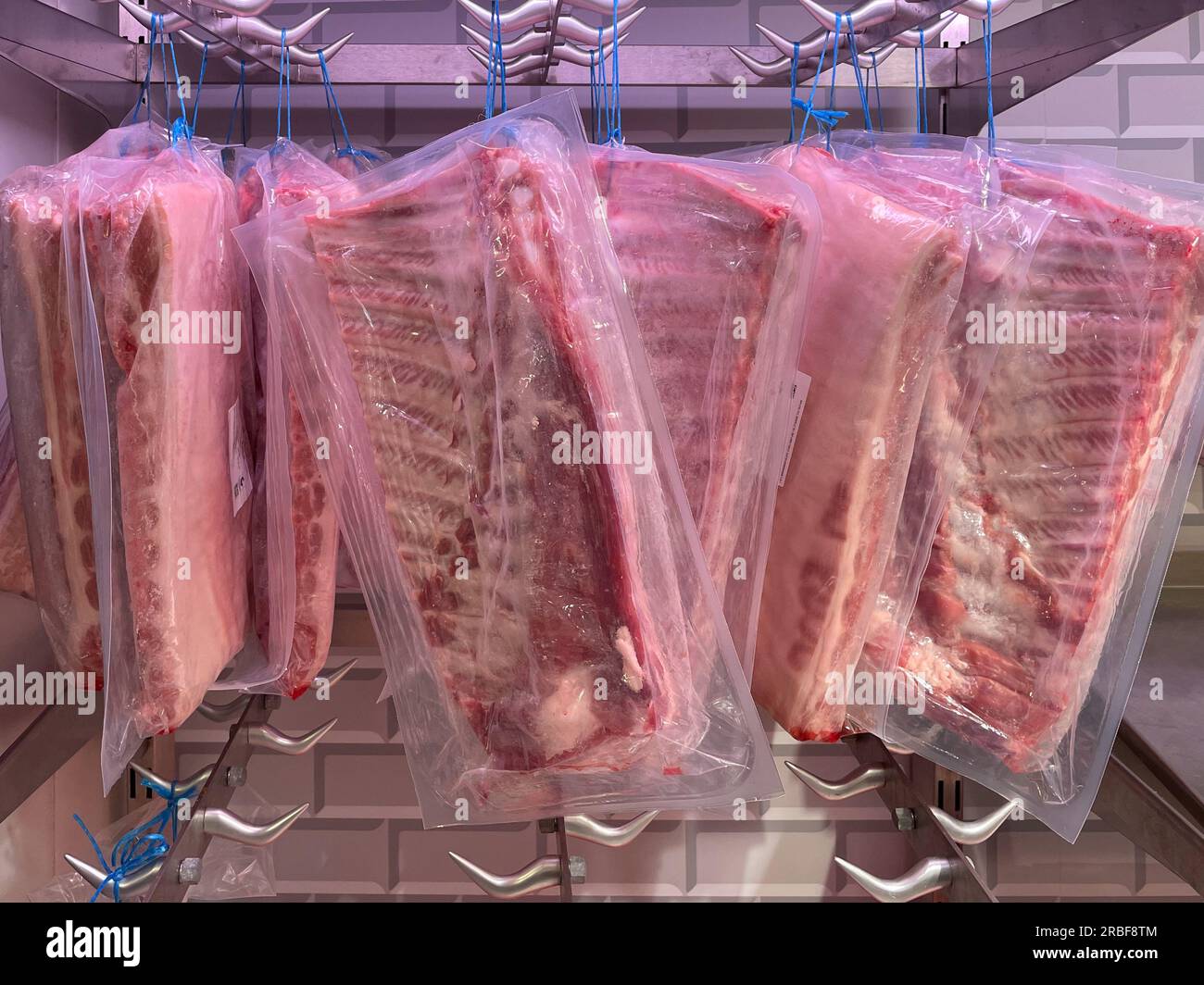 pancetta di maiale appesa in frigorifero confezionata in plastica. Foto Stock