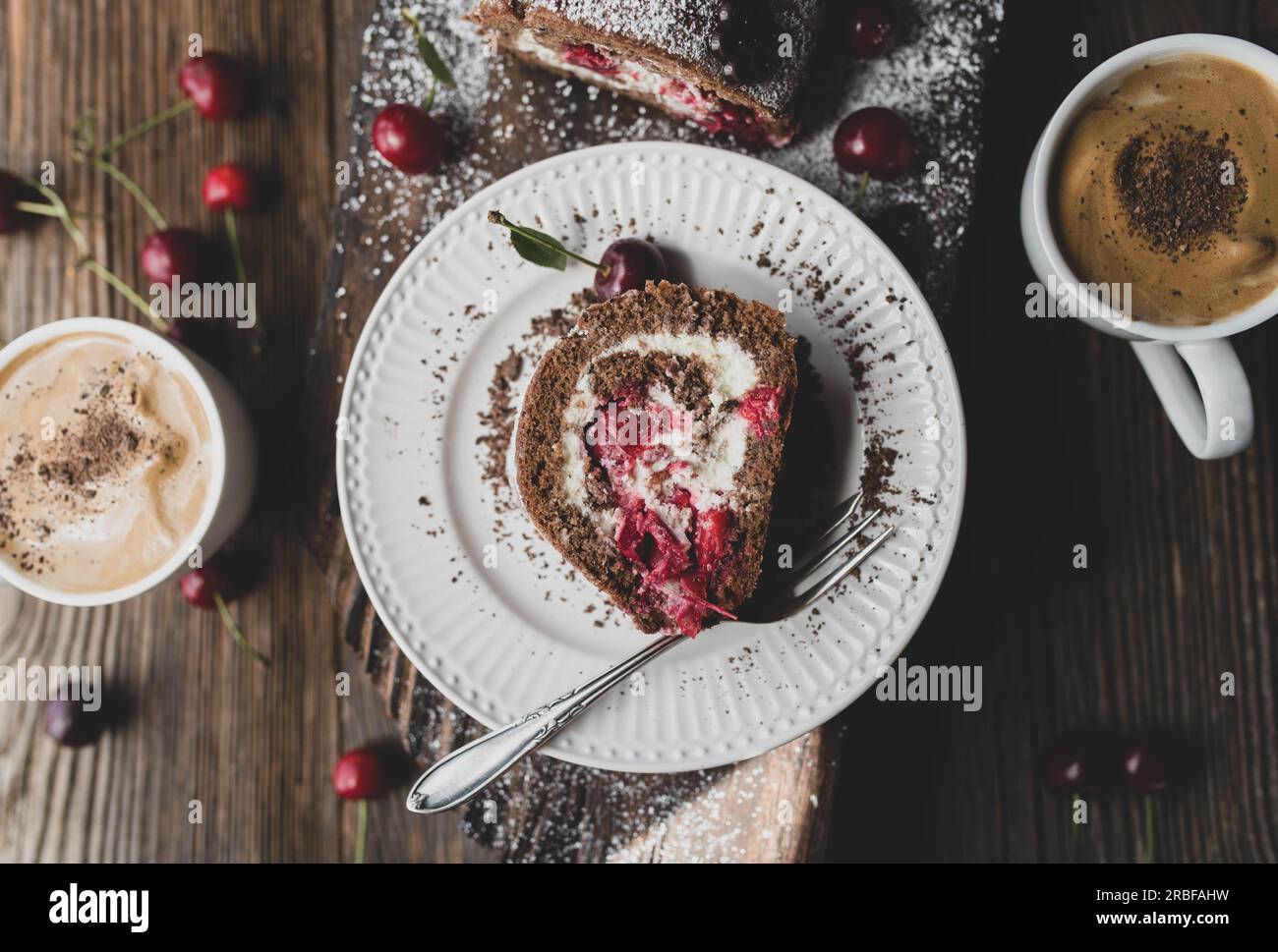 Tazza di caffè e torta con ciliegie su un tavolo di legno Foto Stock