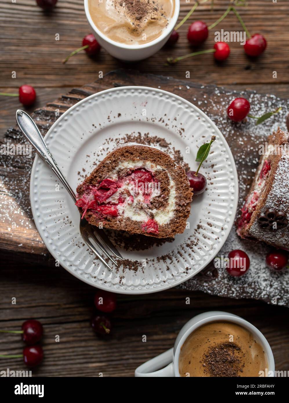 Fetta di roulade di torta della foresta nera su un piatto su sfondo di legno Foto Stock