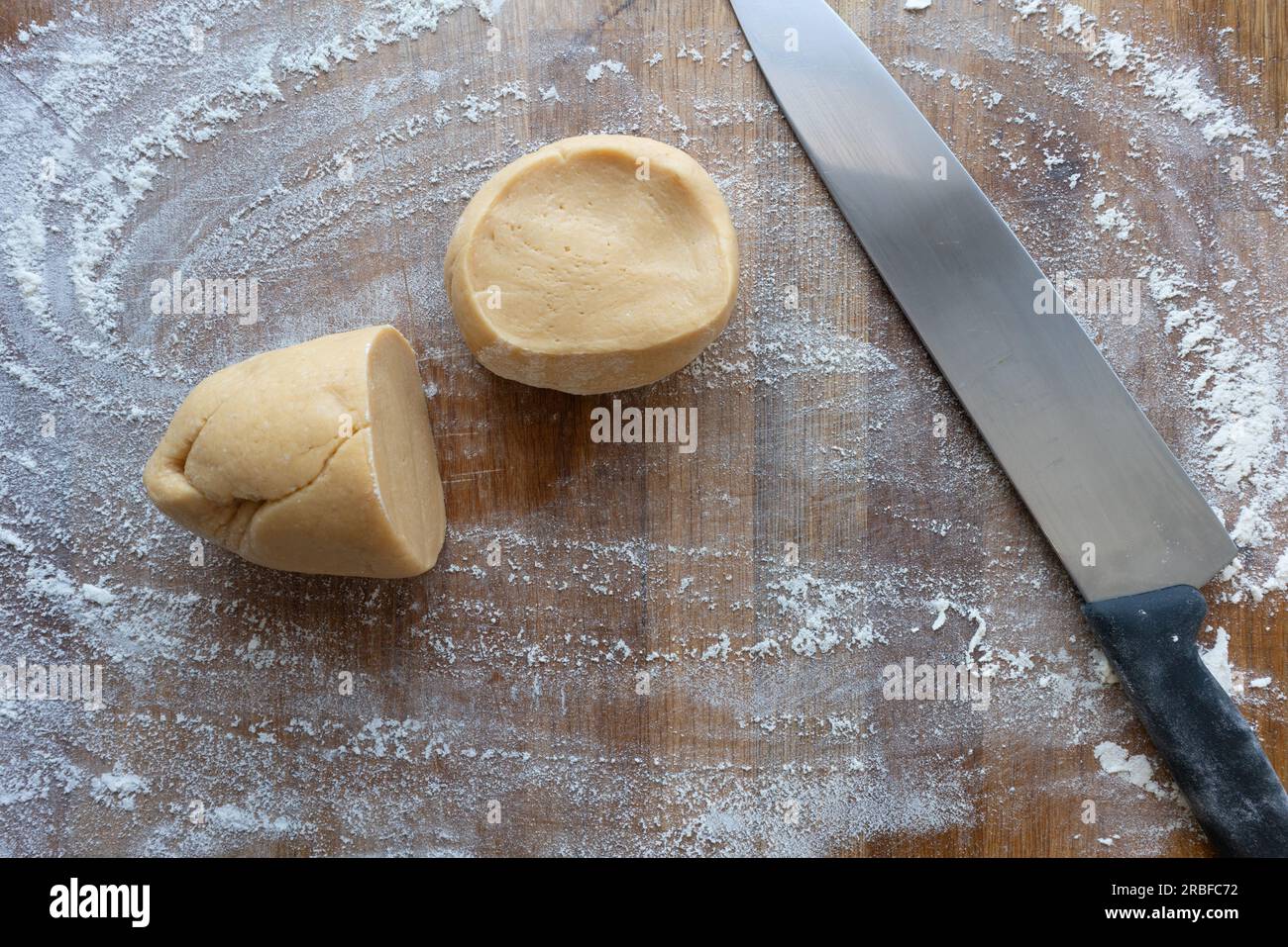 Impastare su un tavolo di legno con un coltello prima di arrotolare Foto Stock